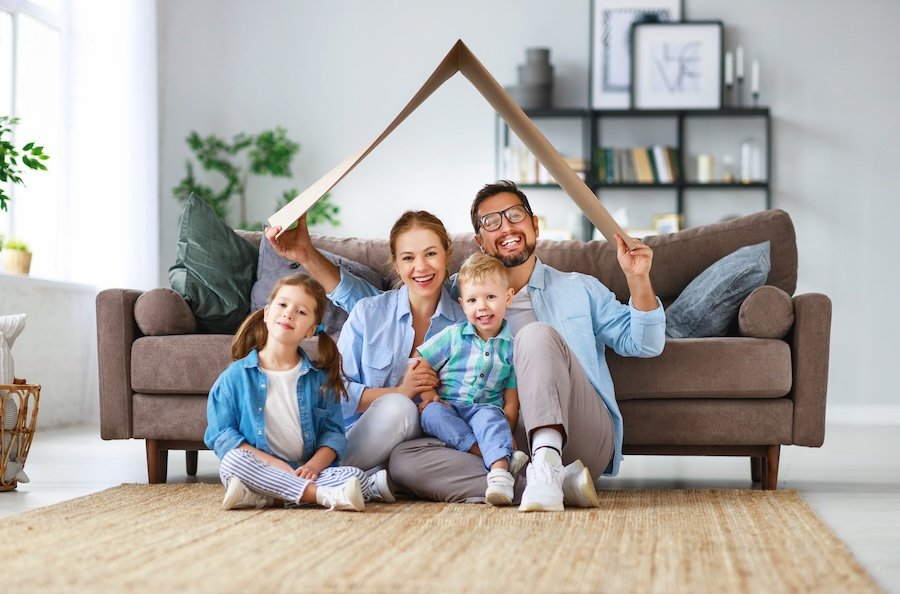 Una famiglia riunita sotto a un tetto di carta, che rappresenta una casa